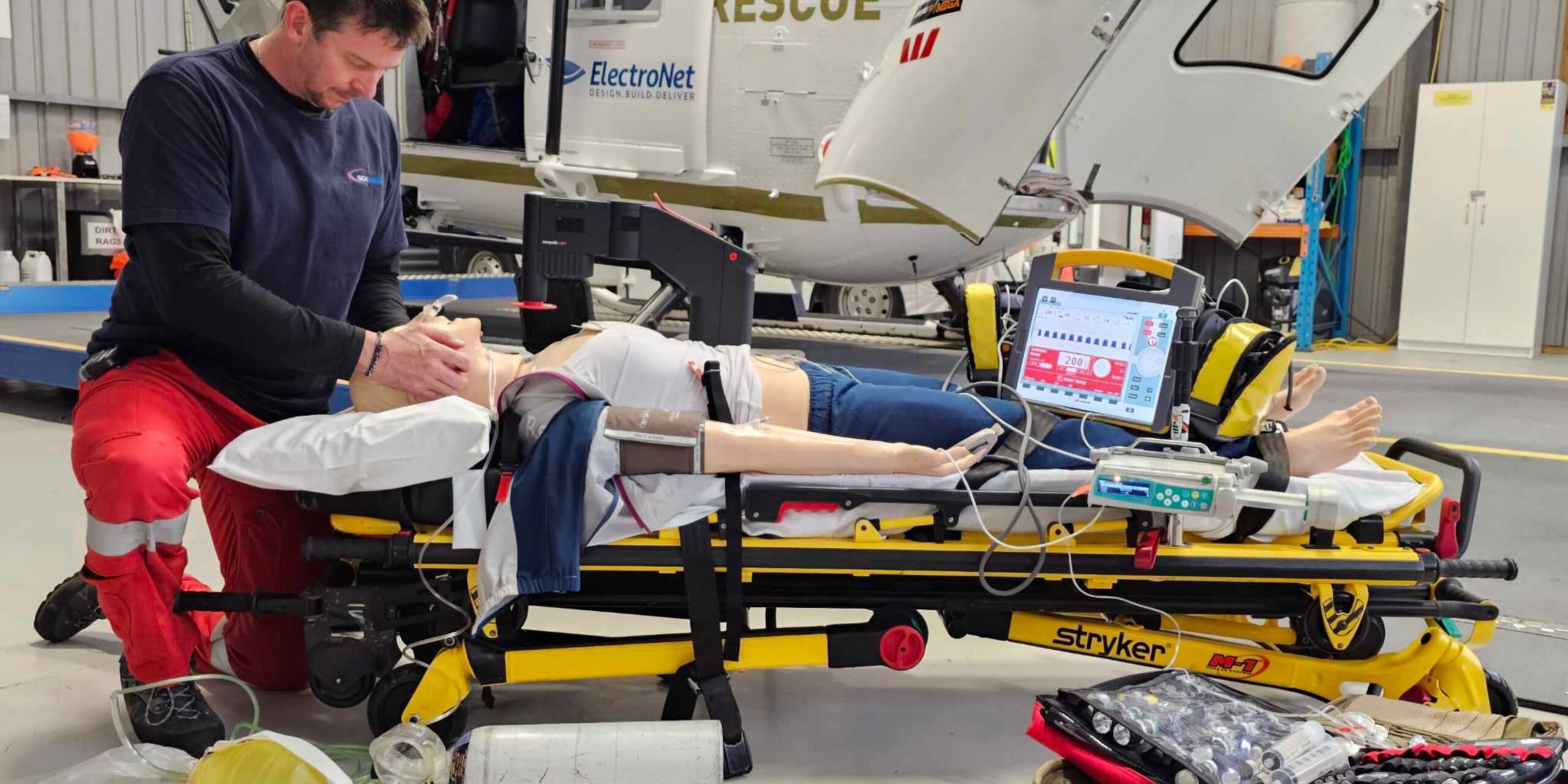 West coast paramedic using mechanical CPR on a mannequine in front of the ROA helicopter