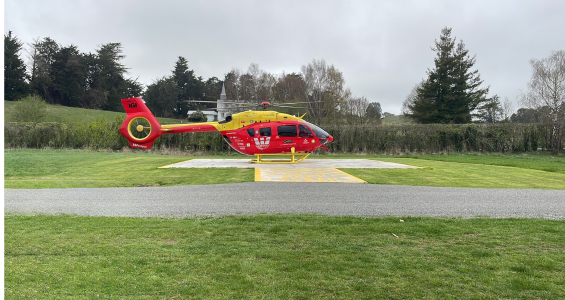 Red helicopter in front of a church in Cheviot